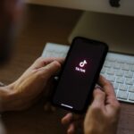 Uma pessoa segurando um iPhone com o logotipo do TikTok na tela.