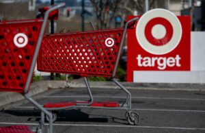 A meta reduz os preços de 3.000 itens ‘entre vestuário, itens essenciais e casa’, já que a inflação permanece acima da meta do Fed Carrinhos de compras vermelhos com o logotipo da Target na frente de uma placa da loja Target.