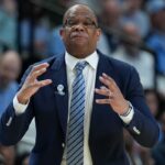 O técnico do Tar Heels da Carolina do Norte, Hubert Davis, instrui sua equipe contra o VCU Rams na primeira metade de um jogo da primeira rodada do torneio masculino da NCAA de 2026 na Bon Secours Wellness Arena.