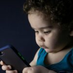 A verificação de idade da Apple falha para alguns – aqui está o que você precisa saber | A foto mostra uma criança segurando um telefone