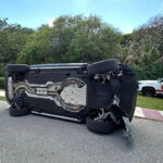 O jogador de golfe Tiger Woods fica ao lado de seu veículo capotado na Ilha de Júpiter, Flórida, na sexta-feira, 27 de março de 2026. (AP Photo/Jason Oteri)