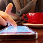 Agora é um bom momento para parar de rolar o apocalipse – veja como | Foto aproximada de um dedo rolando na tela de um smartphone enquanto toma café