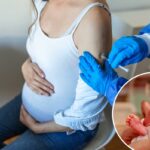 Médico com luvas azuis dando uma injeção de vacina em uma mulher grávida.