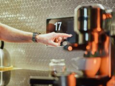 As falhas da casa inteligente da Ikea apontam para um grande problema com a Matter As falhas da casa inteligente da Ikea apontam para um problema com o padrão Matter | Foto de alguém usando uma tela sensível ao toque em uma cozinha ao lado de uma máquina de café