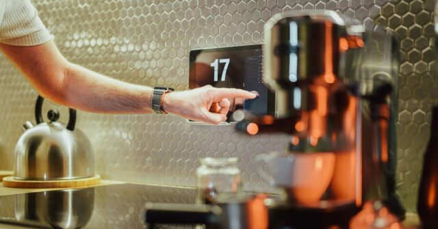 As falhas da casa inteligente da Ikea apontam para um problema com o padrão Matter | Foto de alguém usando uma tela sensível ao toque em uma cozinha ao lado de uma máquina de café
