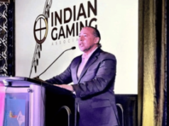 Associação Indiana de Jogos apóia projeto bipartidário do Senado visando mercados de previsão esportiva Presidente da Indian Gaming Association falando no pódio durante conferência sobre política de jogos tribais e regulamentação de apostas esportivas. IGA apóia projeto bipartidário do Senado visando mercados de previsão esportiva