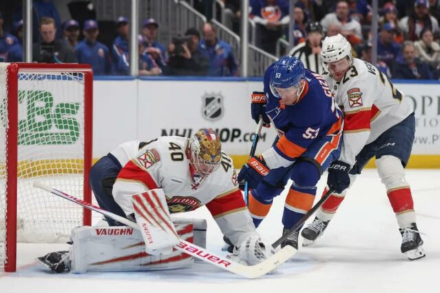 O pivô Casey Cizikas (53) do New York Islanders tenta um chute que ultrapassou o goleiro Daniil Tarasov (40) do Florida Panthers e o pivô Carter Verhaeghe (23) durante o primeiro período de um jogo na UBS Arena em Elmont, NY no sábado, 28 de março de 2026.