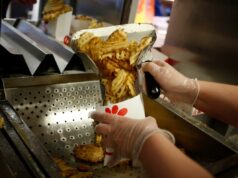 Chick-fil-A muda a receita para batatas fritas com waffle após reação dos fãs Um funcionário usando luvas transparentes prepara batatas fritas com waffles em um recipiente de papel branco em um restaurante Chick-fil-A.