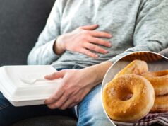 Cientistas identificam por que resistir a um donut pode parecer impossível – mesmo quando você está satisfeito Homem de jeans e moletom cinza esfregando a barriga enquanto segura uma caixa de comida branca com um garfo de plástico no colo.