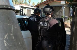 Coloque algemas em gangsters, não em policiais Um policial por trás passa por placas de caixas eletrônicos e placas anunciando serviços de transferência de dinheiro.