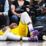 LeBron James faz uma careta de dor depois de cair enquanto subia para uma cesta contra Nikola Jokić durante o quarto período da derrota do Lakers por 120-113 para o Nuggets, em Denver, em 5 de março de 2026.