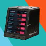 Um dispositivo de mineração de criptomoedas, chamado Magicminer, exibindo vários preços de criptomoedas em sua tela, cercado por moedas bitcoin douradas.