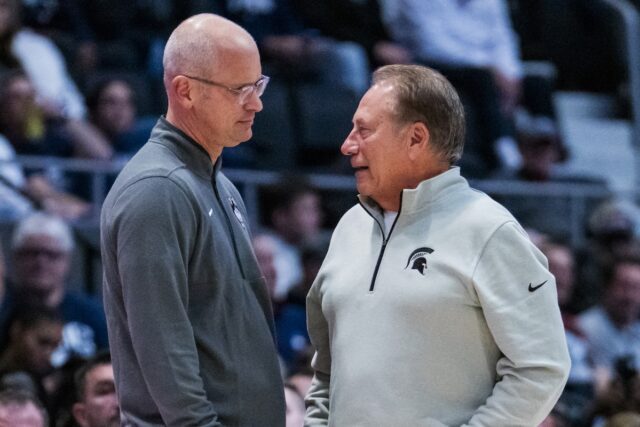 Dan Hurley e Tom Izzo chamam a atenção com aperto Dan Hurley and Tom Izzo chat during a UConn and Michigan State basketball game