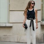 Jill Asemota vista usando óculos escuros vintage pretos, vestido longo de malha de lã cinza Dorothee Schumacher, jaqueta cardigã de malha de lã cinza Dorothee Schumacher combinando, meias de algodão brancas, tênis Samba de couro branco Adidas, em 04 de novembro de 2023 em Berlim, Alemanha.