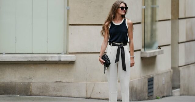 Estas 18 calças pull-on têm um controle de barriga surpreendentemente Jill Asemota vista usando óculos escuros vintage pretos, vestido longo de malha de lã cinza Dorothee Schumacher, jaqueta cardigã de malha de lã cinza Dorothee Schumacher combinando, meias de algodão brancas, tênis Samba de couro branco Adidas, em 04 de novembro de 2023 em Berlim, Alemanha.