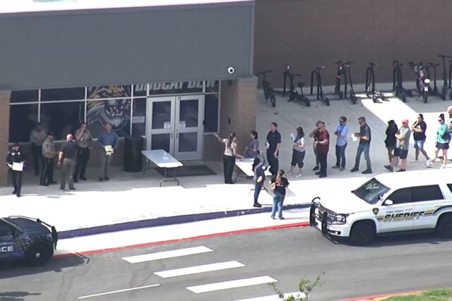 Um policial parado do lado de fora da Hill Country College Preparatory High School.