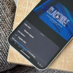 Mulher usando o telefone ao lado de um grande logotipo 3D do YouTube e de um ícone do aplicativo NotebookLM.