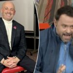 Dois homens, um de terno e outro com roupas esportivas, sentam-se em cadeiras vermelhas e sorriem para a câmera.