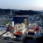 A battery materials factory is lit up at dusk.