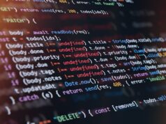 Hacker sequestra projeto de código aberto Axios, usado por milhões, para enviar malware Close-up of computer screen showing colorful programming code lines with syntax highlighting and blurred light reflections.