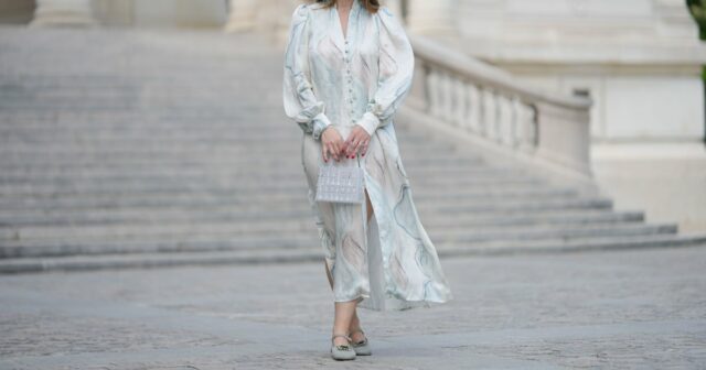 PARIS, FRANÇA - 12 DE MAIO: Gabriella Berdugo usa óculos escuros, brincos, vestido longo xadrez branco azul e verde com mangas compridas e estampa floral, cinto de couro marrom, bolsa Kelly Hermes azul, mules / sapatos amarelo pastel claro com salto em formato de coração de Kat Maconie, durante uma sessão de fotos de moda de estilo de rua, em 12 de maio de 2024 em Paris, França. (Foto de Edward Berthelot/Getty Images)