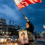 As pessoas agitam bandeiras enquanto protestam em apoio ao governo iraniano no centro de Teerã.