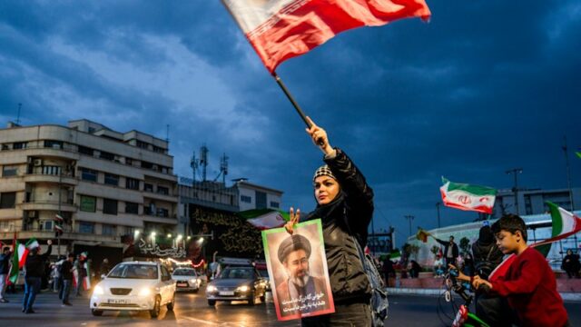 As pessoas agitam bandeiras enquanto protestam em apoio ao governo iraniano no centro de Teerã.