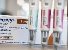 Jabs para perda de peso não são solução rápida, alerta chefe de saúde Dr. Sakthi Karunanithi em um estúdio da BBC com um fundo de árvores e casas contra um céu azul. Dr. Sakthi tem cabelo branco penteado para trás e uma barba bem cuidada e está vestindo um paletó cinza, gravata floral verde e camisa listrada