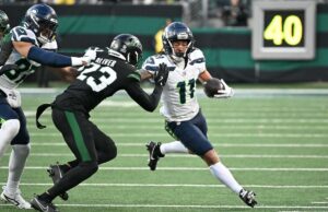 Jaxon Smith-Njigba consegue um contrato de US$ 168 milhões depois de ajudar os Seahawks a vencer o Super Bowl Dois jogadores de futebol, um com camisa branca e outro com camisa preta, em ação durante um jogo.