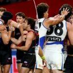 Um árbitro da AFL intervém enquanto jogadores de Essendon e North Melbourne se empurram e se empurram.