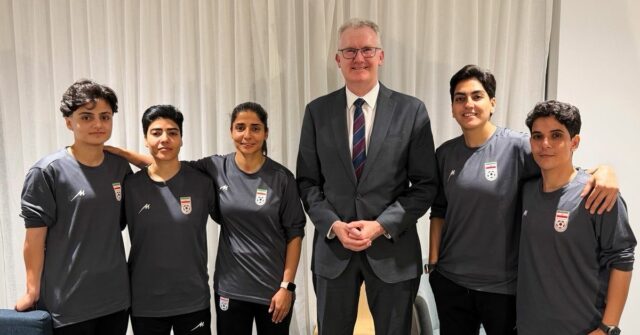 Nesta foto fornecida pelo gabinete do Ministro de Assuntos Internos da Austrália, Tony Burke, o Ministro Tony Burke, no centro, posa em um local não revelado com cinco jogadoras de futebol iranianas que receberam asilo na Austrália, terça-feira, 10 de março de 2026. (Ministério de Assuntos Internos da Austrália via AP)