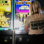 Um técnico da cena do crime do Gabinete do Xerife do Condado de Flagler fotografa máquinas de jogos estilo caça-níqueis iluminadas exibindo gráficos brilhantes e valores de jackpot. Jogos de azar disfarçados capturam dinheiro de máquinas em empresas do condado de Flagler