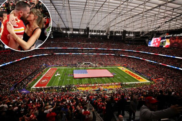 Uma vista do Allegiant Stadium cheio de gente e uma enorme bandeira americana cobrindo o meio do campo antes do Super Bowl LVIII.