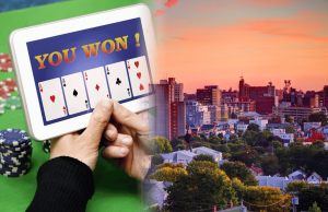 Legisladores do Maine promovem projeto de lei que proíbe jogos estilo cassino de sorteios online Legisladores do Maine promovem projeto de lei que proíbe jogos de sorteios online no estilo cassino. Mão segurando um tablet mostrando um jogo de cartas online vencedor ao lado de fichas de pôquer, próximo ao horizonte do pôr do sol de Portland, Maine.