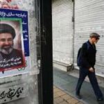 Um homem caminha ao lado de um cartaz com uma foto do Irã