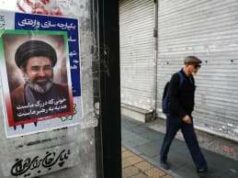 Líder Supremo Khamenei no Irã, mas evitando aparições públicas, diz enviado russo Um homem caminha ao lado de um cartaz com uma foto do Irã