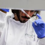 A man pipettes a liquid into a small tube.