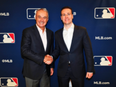 MLB e CFTC firmam pacto de integridade enquanto liga recorre ao Polymarket para mercados de previsão O comissário da MLB, Rob Manfred, e o presidente da CFTC, Mike Selig, apertam as mãos no evento de anúncio de parceria da Liga Principal de Beisebol com logotipos da MLB como pano de fundo