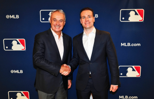 MLB e CFTC firmam pacto de integridade enquanto liga recorre ao Polymarket para mercados de previsão O comissário da MLB, Rob Manfred, e o presidente da CFTC, Mike Selig, apertam as mãos no evento de anúncio de parceria da Liga Principal de Beisebol com logotipos da MLB como pano de fundo