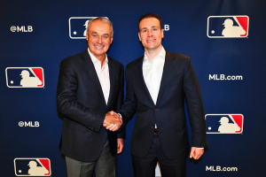 MLB e CFTC firmam pacto de integridade enquanto liga recorre O comissário da MLB, Rob Manfred, e o presidente da CFTC, Mike Selig, apertam as mãos no evento de anúncio de parceria da Liga Principal de Beisebol com logotipos da MLB como pano de fundo