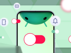 Meu telefone precisava de uma atualização até que eu alterei essas configurações Mascote do Android entre caixas de papelão etiquetadas para aplicativos, capturas de tela, notificações e distrações, em frente à tela de um smartphone, com uma vassoura apoiada nas caixas.