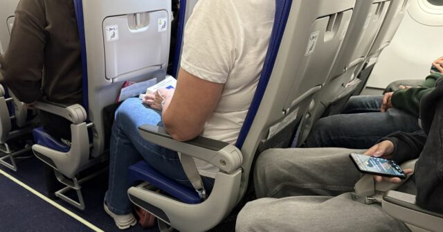 Meu voo será cancelado? O que saber sobre o conflito Passageiros sentados na cabine de um avião com cintos de segurança visíveis, espaço para as pernas e pertences pessoais durante um voo comercial