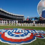 Um homem de terno azul com gravata listrada e lenço branco no bolso.