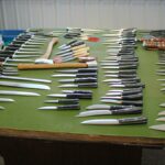 Uma mesa com feltro verde com Facas Bark River dispostas em cima.