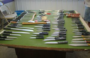 Michigan Knifemaker fecha loja após admitir usar aço chinês e rotulá-lo como feito nos EUA Uma mesa com feltro verde com Facas Bark River dispostas em cima.