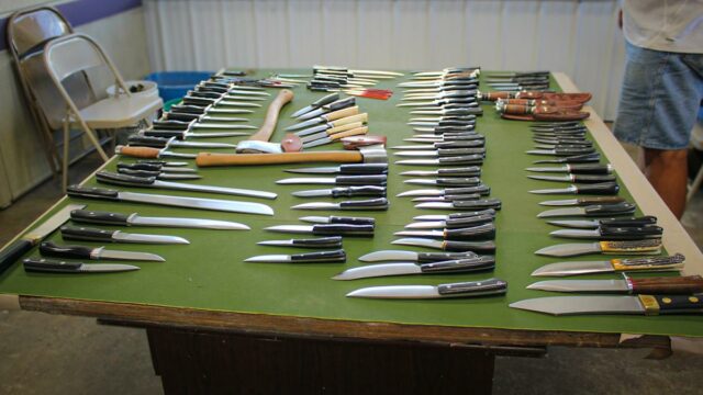 Uma mesa com feltro verde com Facas Bark River dispostas em cima.