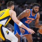 Mitchell Robinson, que pegou 22 rebotes, acertou Ivica Zubac durante a vitória dos Knicks por 101-92 sobre os Pacers em 13 de março de 2026, em Indianápolis.