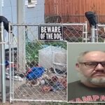 Uma cerca com uma placa de alerta de cachorro.