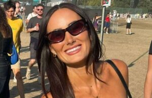 Mulher descobriu que tinha câncer cerebral terminal depois que mala caiu em sua cabeça Lauren Macpherson está em um campo de festival. As pessoas podem ser vistas em multidões atrás dela. Ela segura uma bebida rosa em um copo de plástico na mão esquerda e uma bolsa preta no ombro. Ela usa óculos escuros pretos, tem cabelos castanhos compridos e sorri para a câmera.