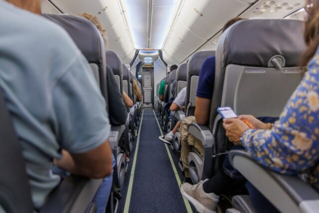 Stock image: a view of a plane aisle with passengers in their seats.